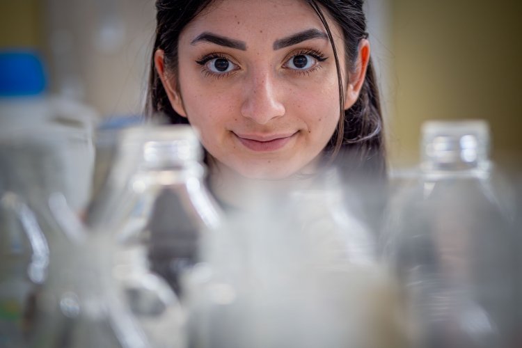 Melissa Spigelman with laboratory glassware in the foreground.