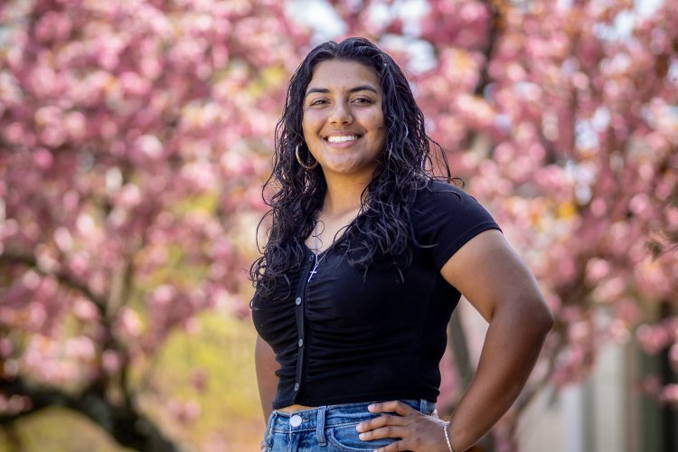 Woman smiling with cherry flowers behind her. 