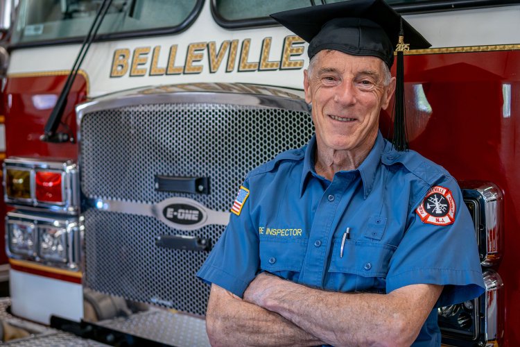 Ralph Castellano celebrates his Montclair State University graduation at the Belleville Fire Department, wearing his uniform and graduation cap.