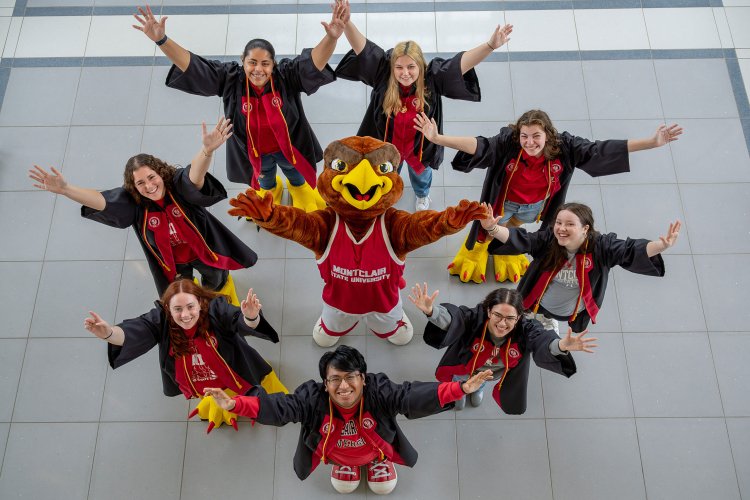 Graduates pose with Rocky in a circle.