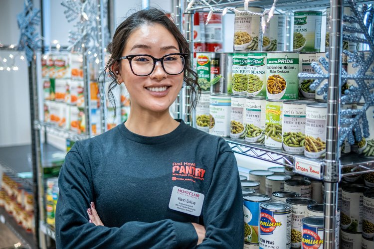 Kaori Sakae stands, arms crossed, in front of food-filled shelves at Red Hawk Pantry.