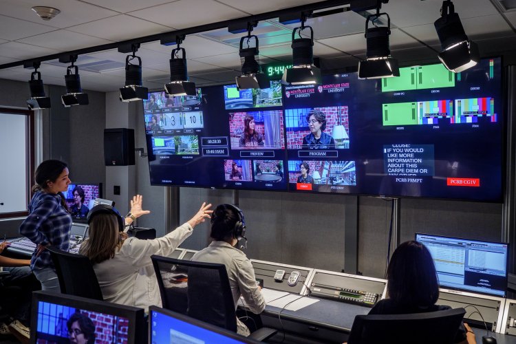 Students working in a television control room, monitoring multiple screens and coordinating a live studio production.