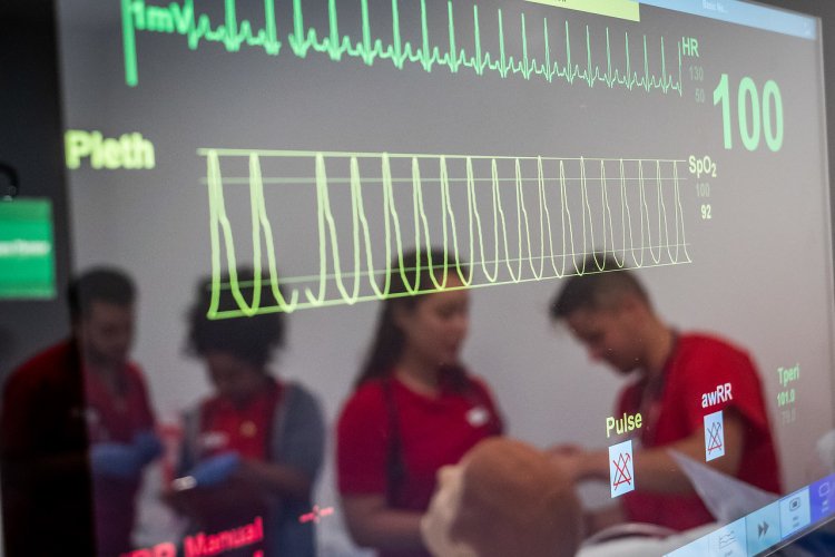 Medical machine with yellow and green streaks, through the reflection there are nursing students in scrubs.