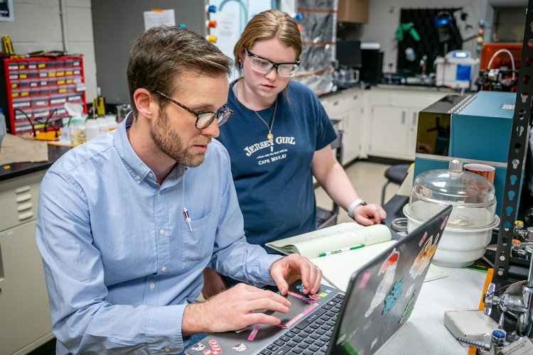 Professor working on a computer as their student watches.