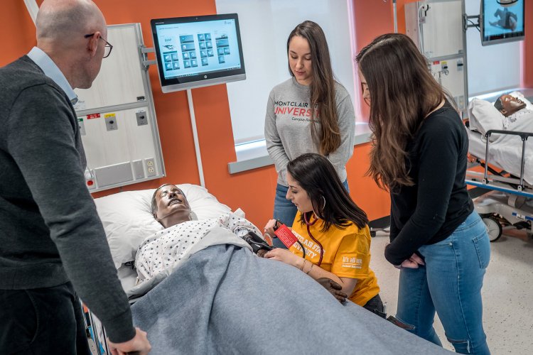 Professor and three students working on a mannequin patient.