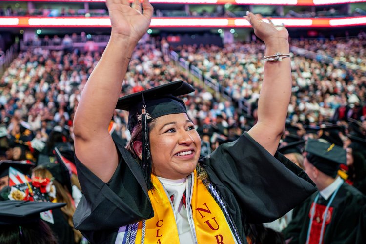 Nursing graduate waving to the crowd at commencement