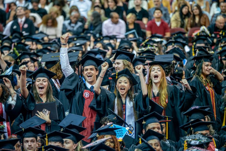 Group of graduates celebrating at commencement with their cap and gown.