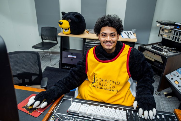 Ethan Garcia wearing part of his Deacon the Bear costume at a soundboard.