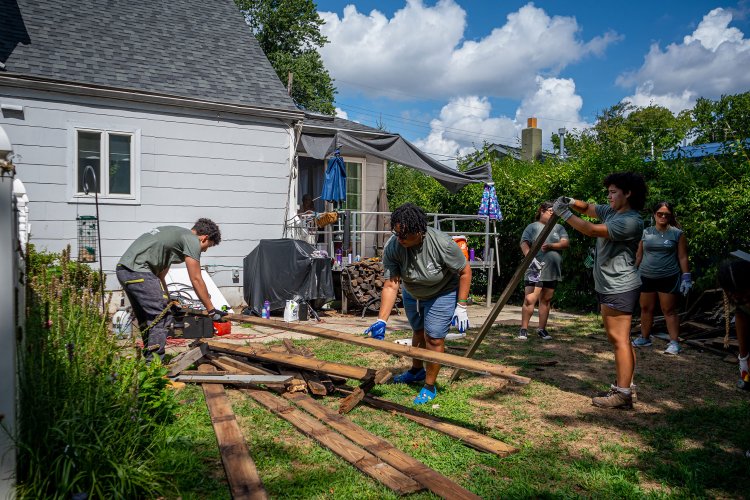 Students working on an elderly woman's home outside.