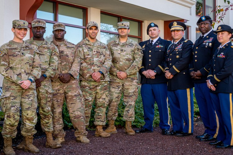 Military personnel posing together with their hands over one another.
