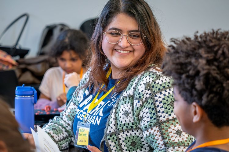 Female is smiling with glasses on smiling talking to a child.