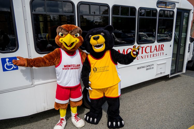 Rocky and Deacon standing in front of a Montclair State University campus shuttle.