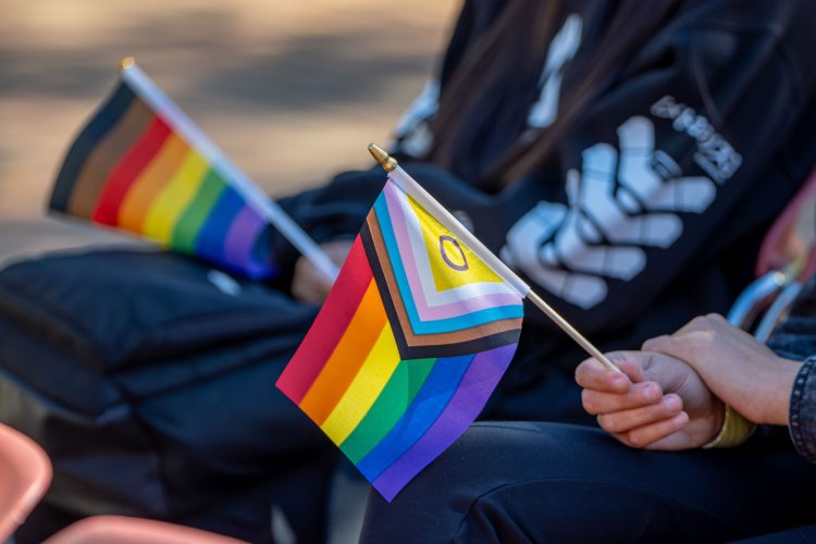 Two people holding the LGBTQ+ flags.