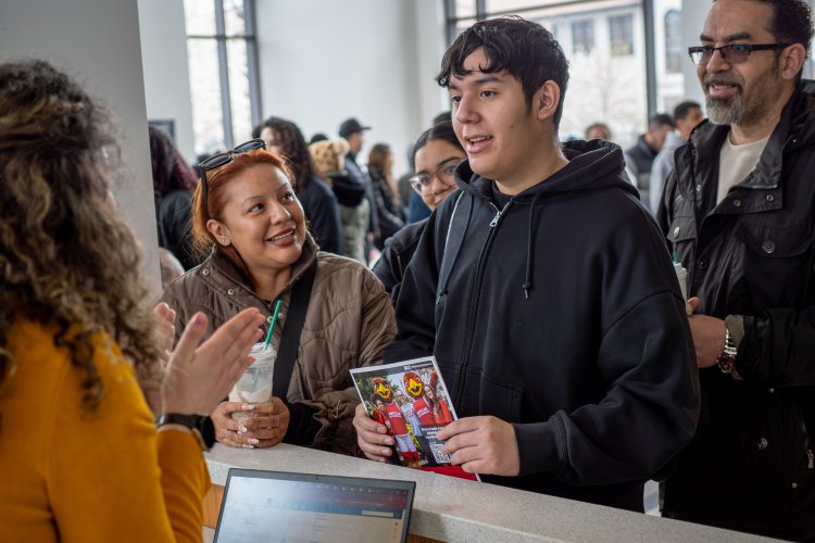 A student in the center, with his parents, talk with a college staff member.