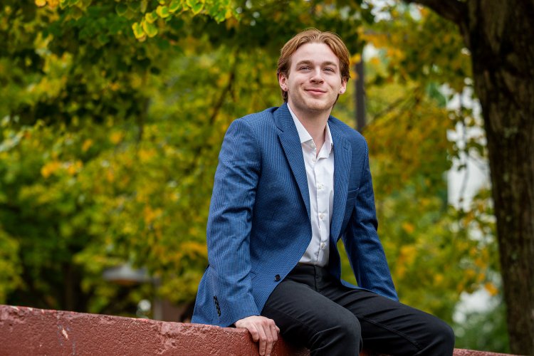 Ben Coulson sits on a wall on campus.