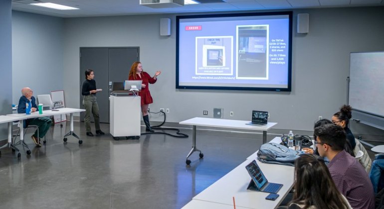 students presenting in front of a projection screen