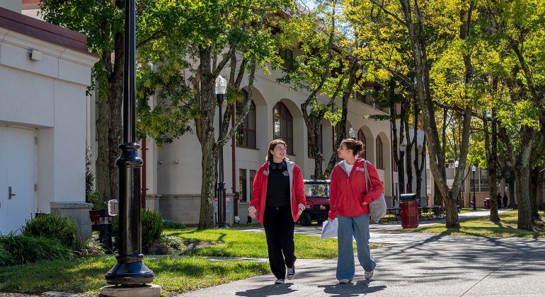 two students wearing red jackets walking on Montclair campus
