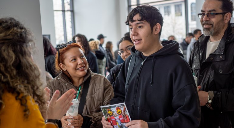 A student in the center, with his parents, talk with a college staff member.