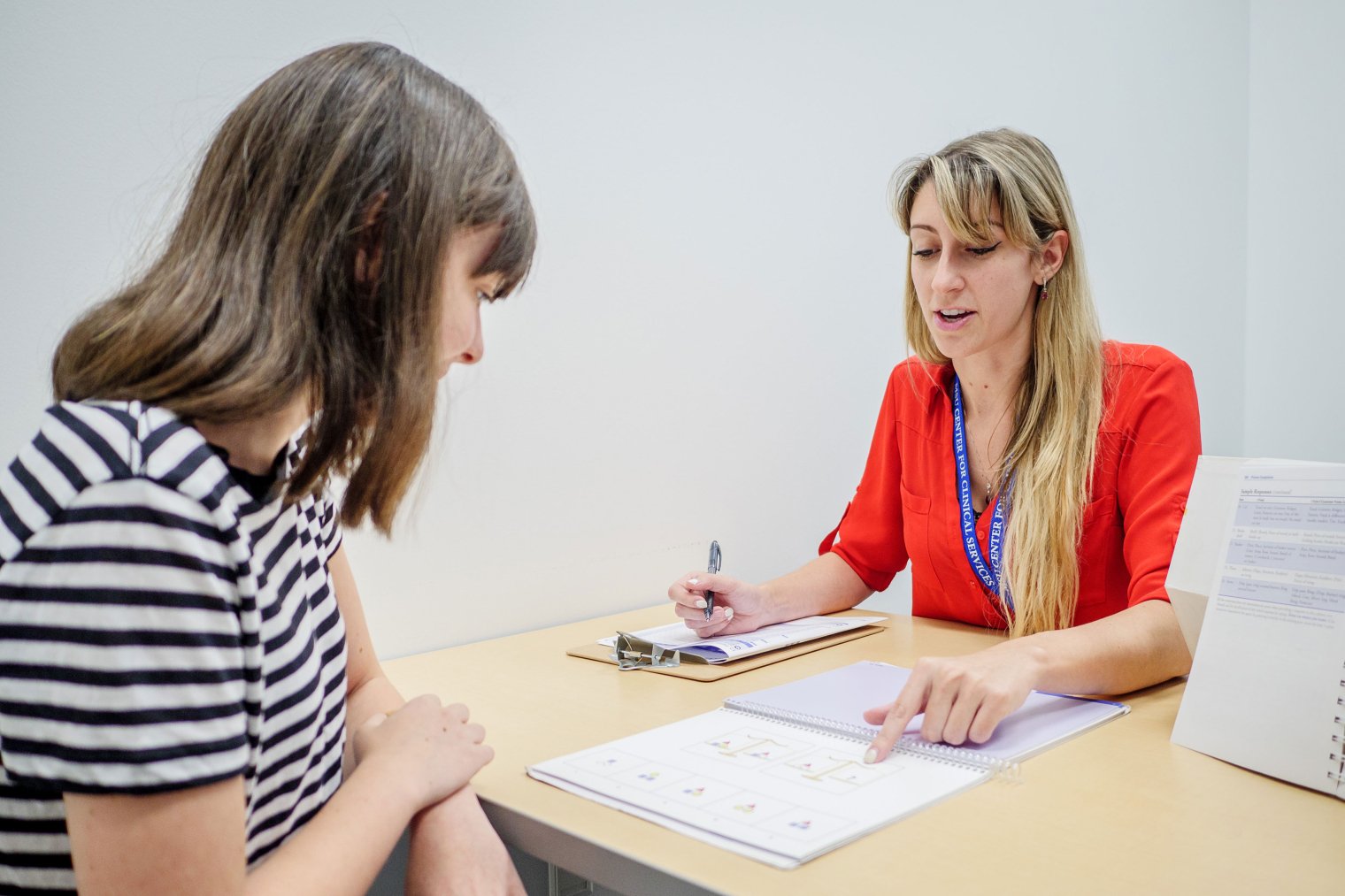 Clinical psychology student worker speaking with a person over a desk