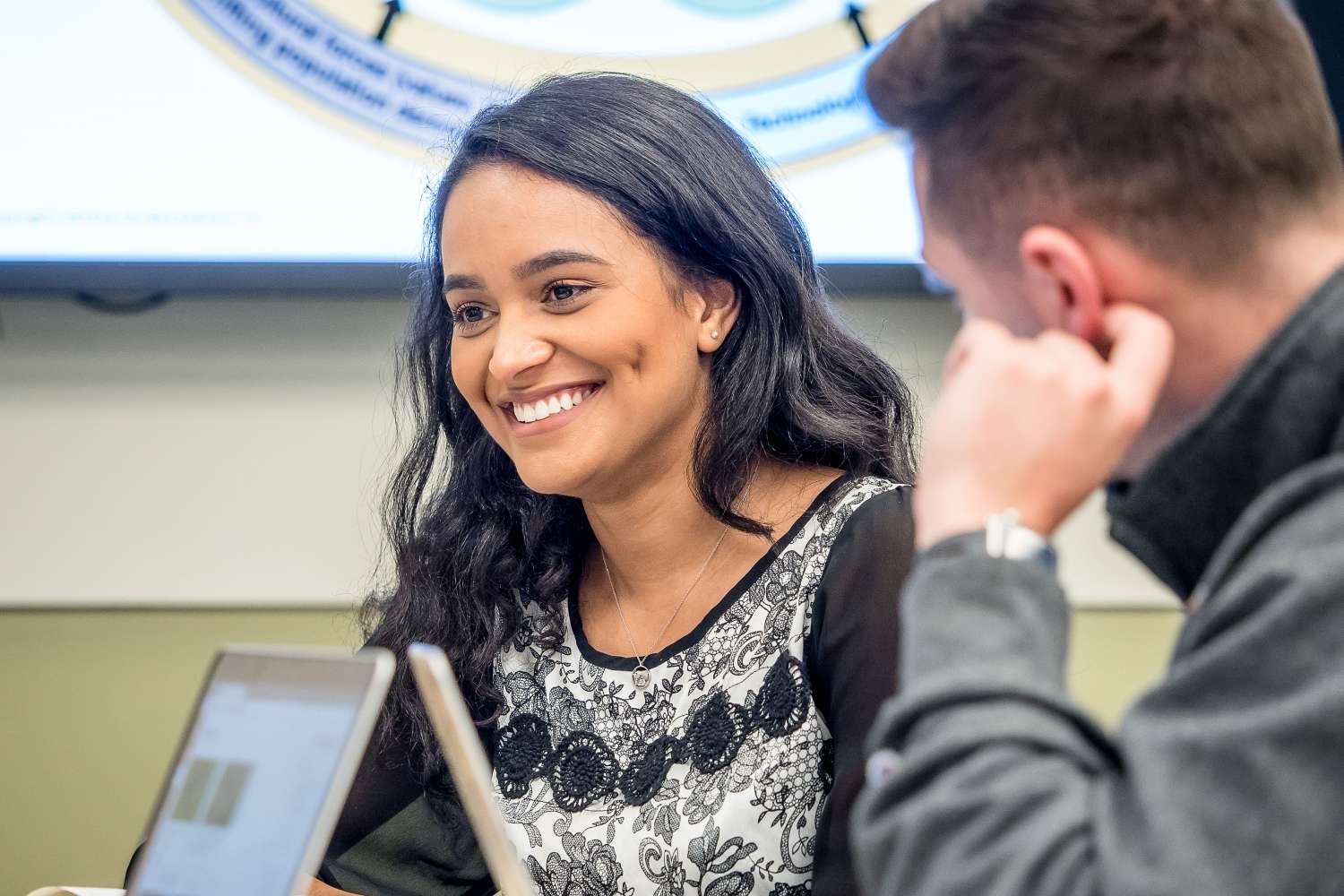 Student smiling while talking to other students.