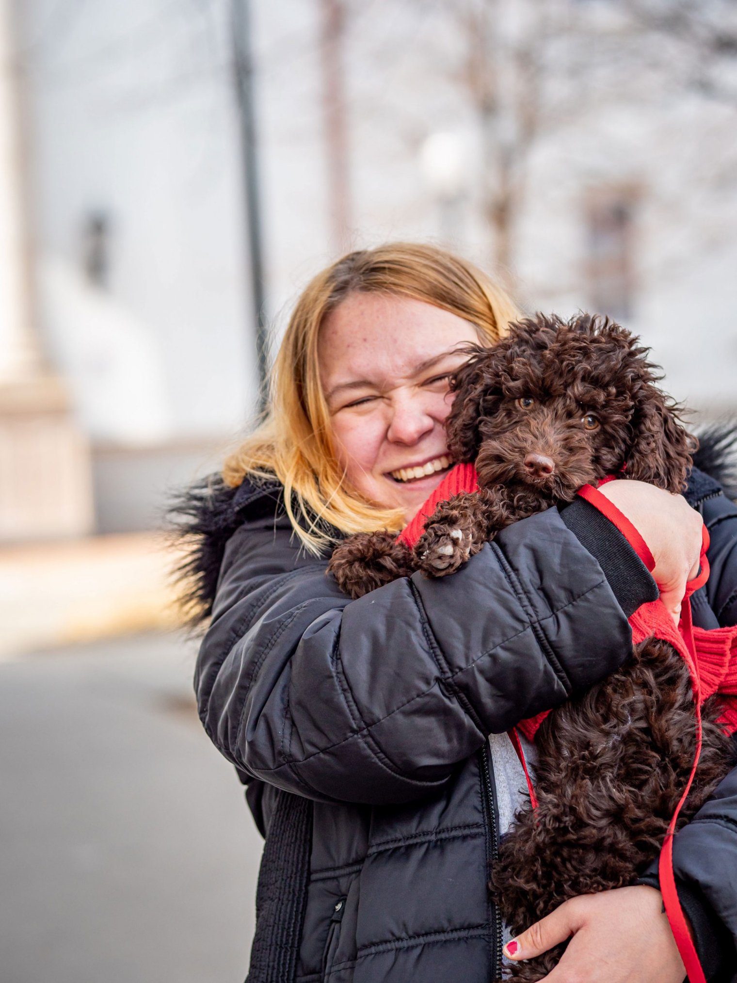 student holds a puppy on campus