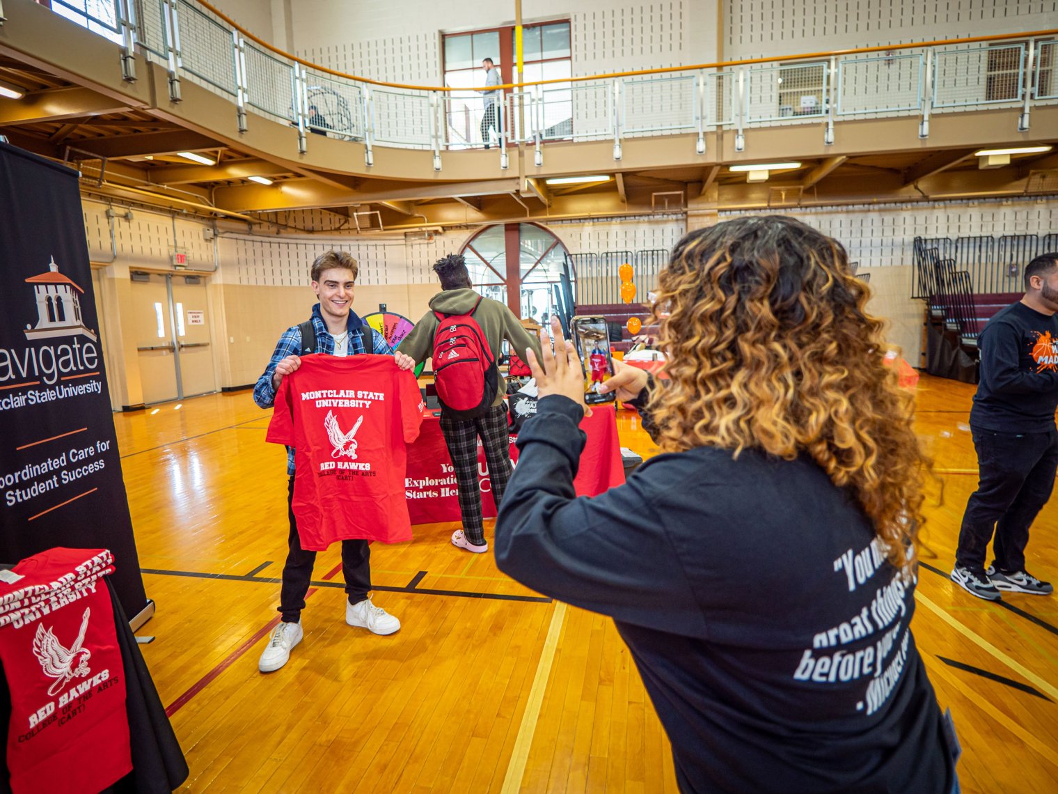 Female student takes photo of male student holding red T-shirt.