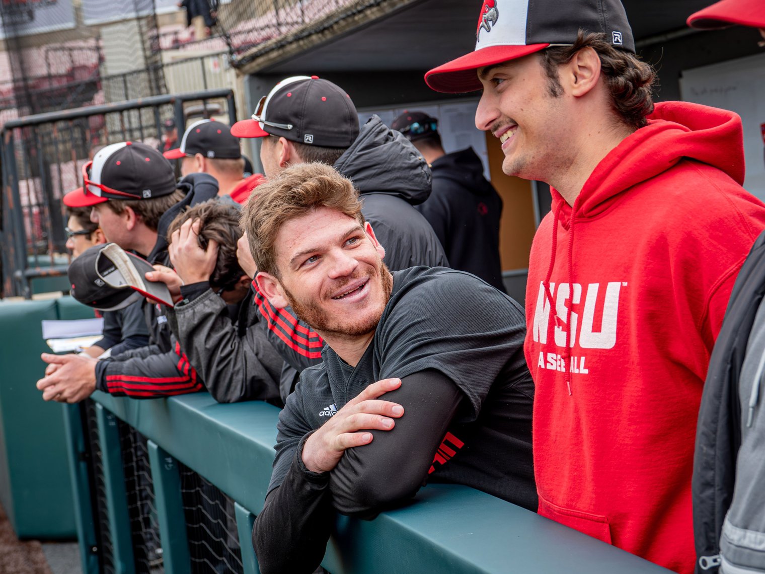 Players smile and talk in the dugout.