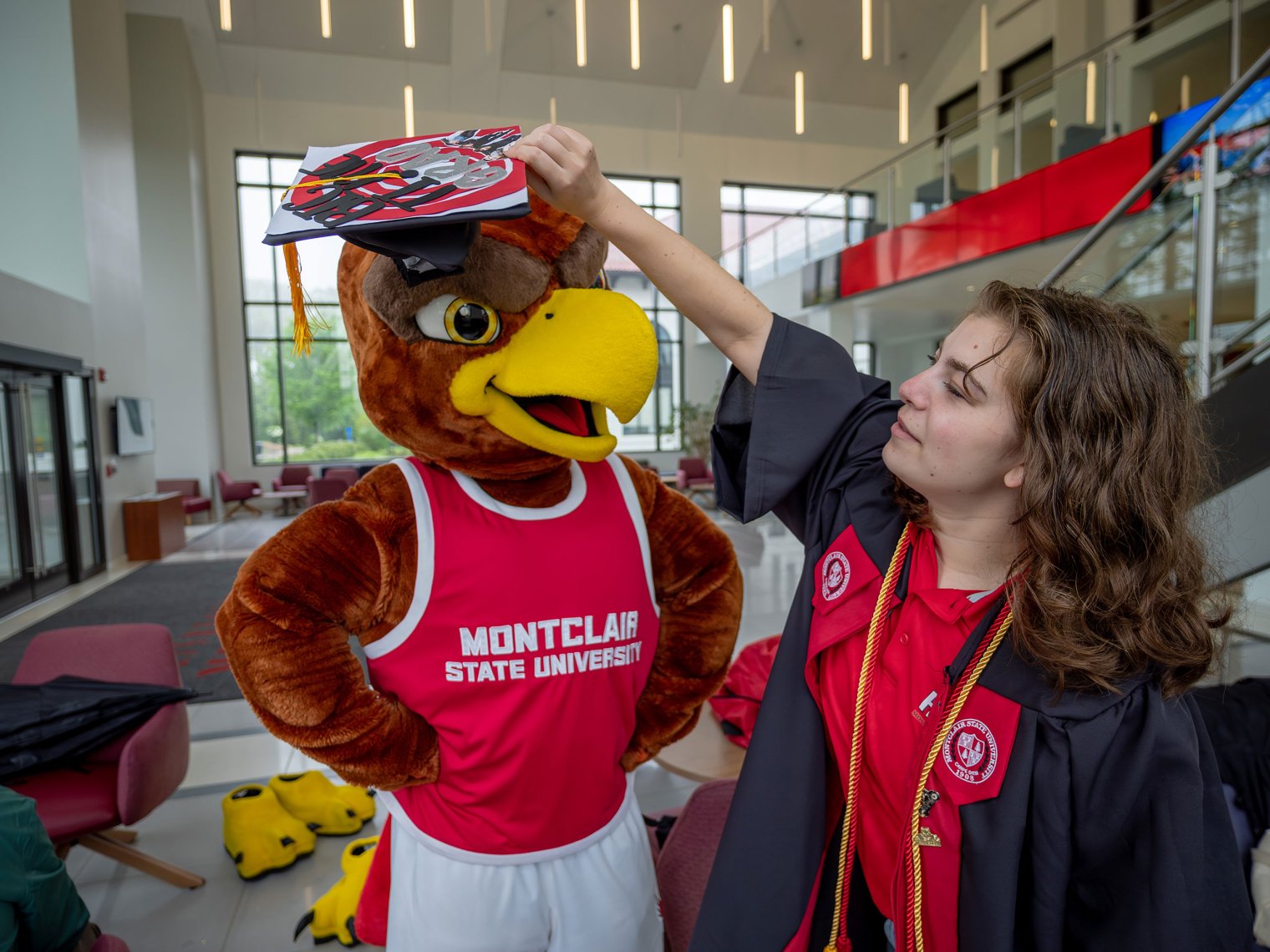 A student places a mortarboard on Rocky’s head.