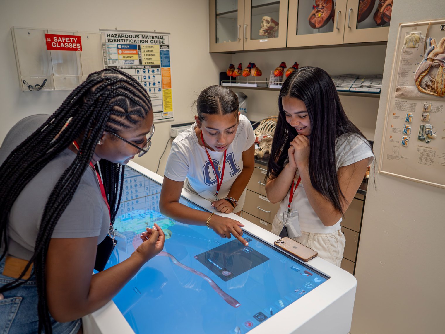 Three students in the pre-med program gather around an interactive 3D anatomy visualization system to study and understand the human body.
