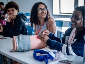 Students over a CPR doll discussing. 