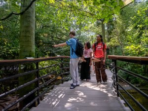 Students at a zoo pointing over a bridge.