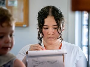 Student is writing down notes in a lab coat.