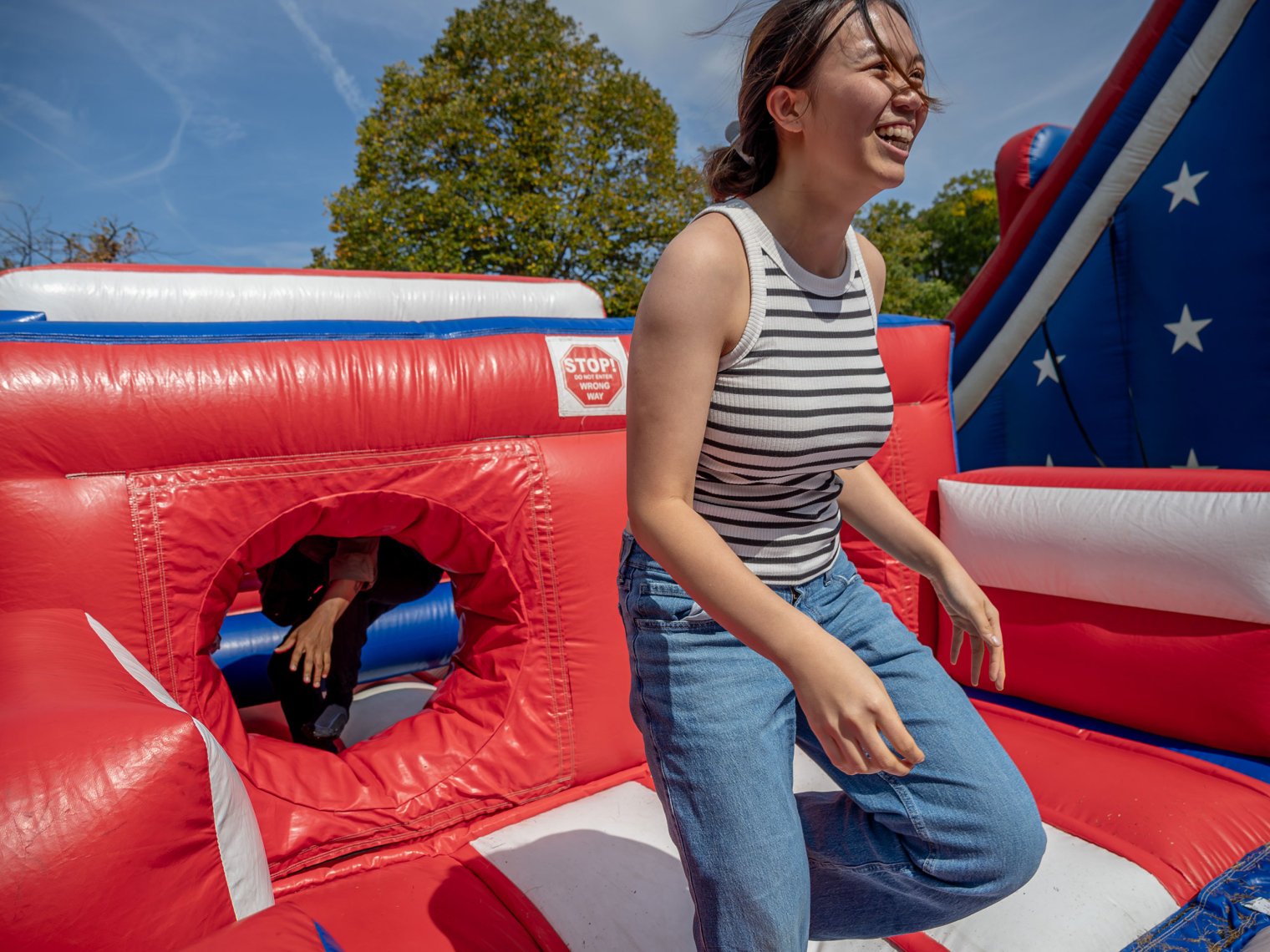 A student smiles after sliding down a large red, white, and blue patriotic slide set up to promote voter registration during National Voter Registration Day.