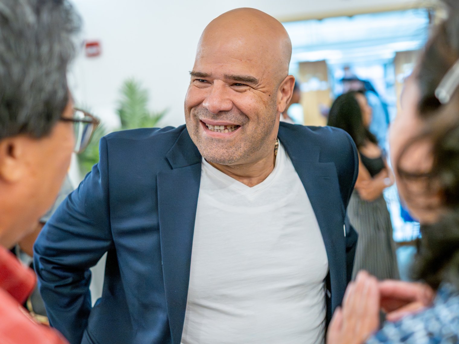 Man is pictured smiling with a blue suit and white shirt underneath.