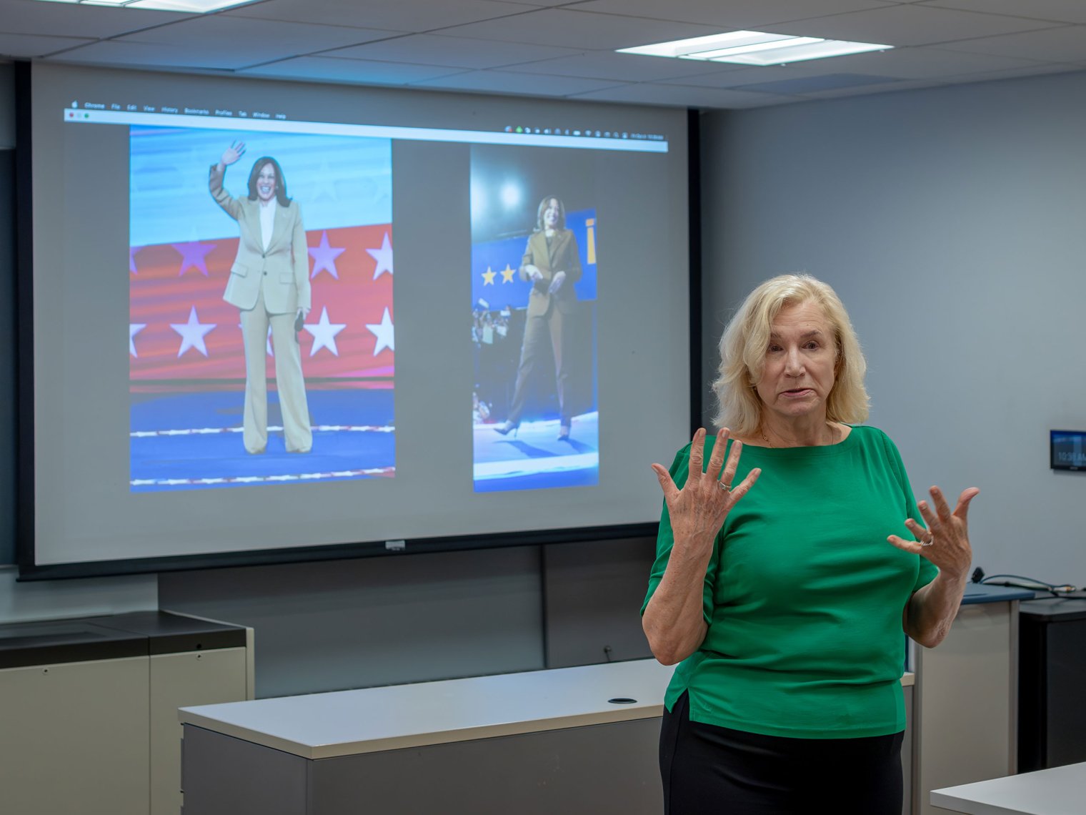 A professor gestures from the front of a filled classroom.