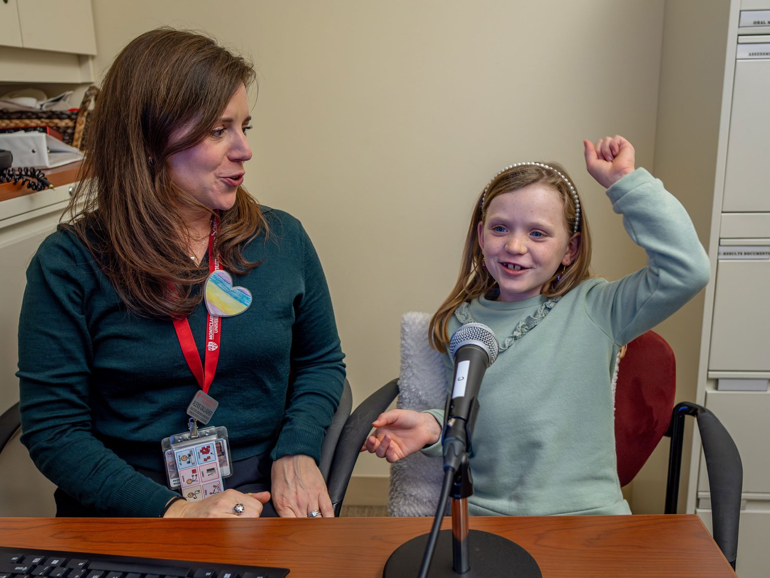 Colette raises an arm in celebration during her speech therapy session under the guidance of Alexis Gallagher. 