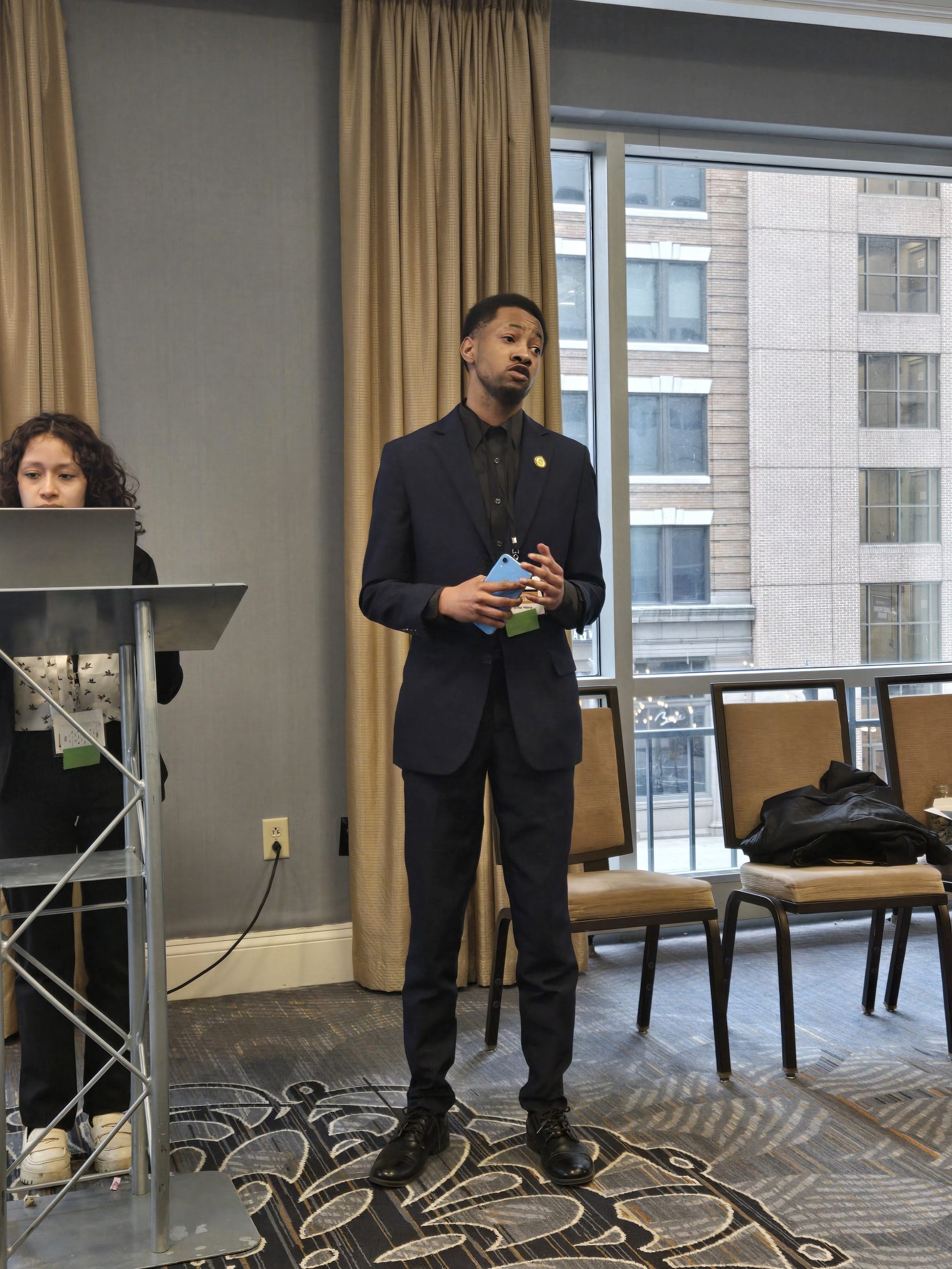 Man in a black suit is seen presenting. 
