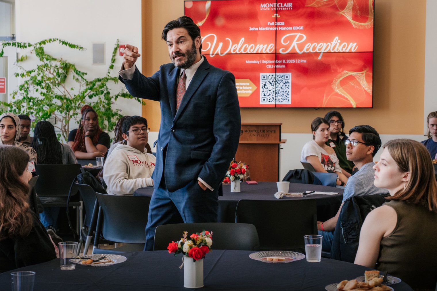 President Jonathan Koppell stands addressing students at the John Martinson Honors EDGE reception, gesturing as attendees seated at round tables listen attentively.