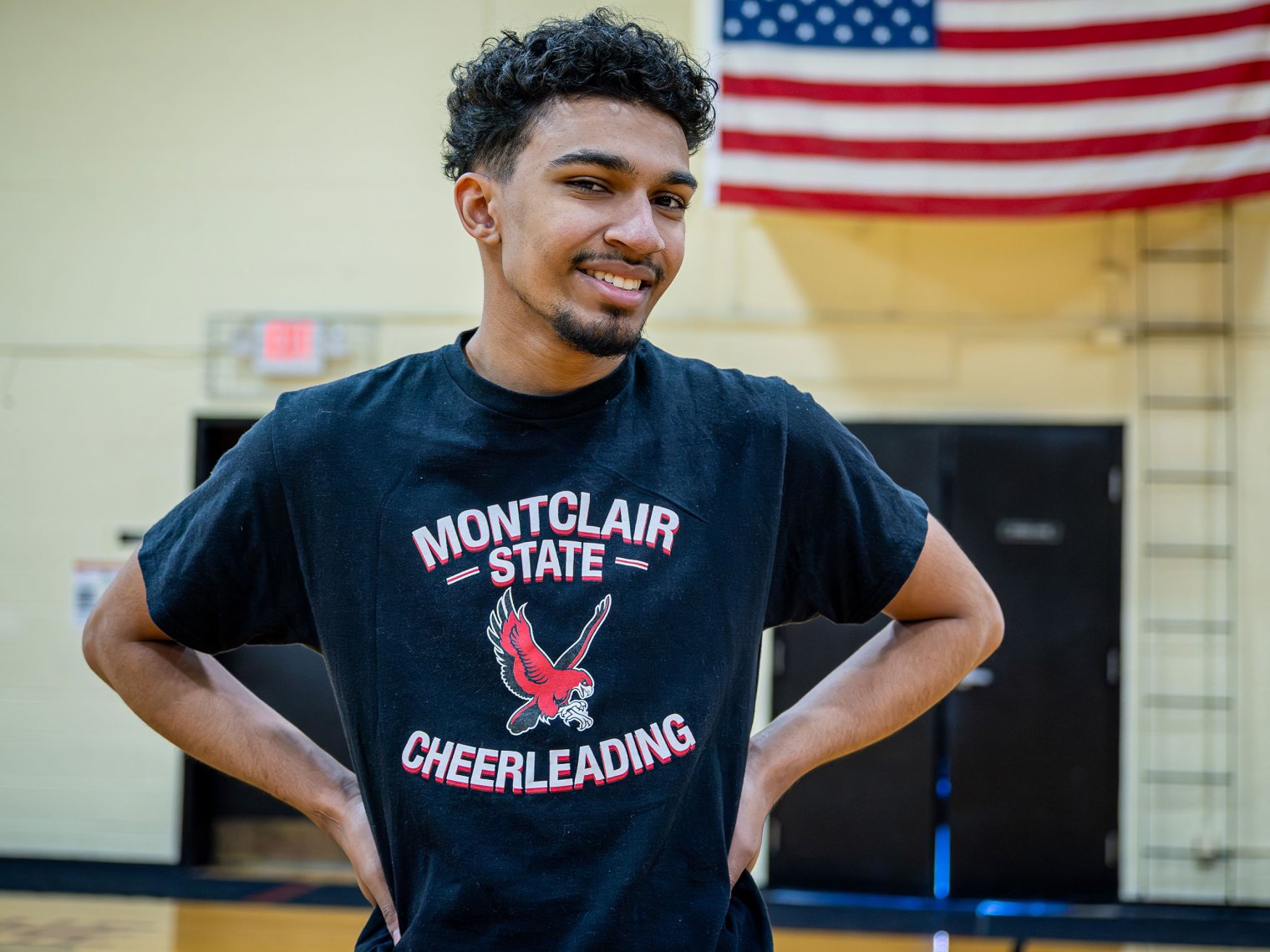 Bryce is smiling with his hands on his hips wearing a MSU cheerleading shirt.
