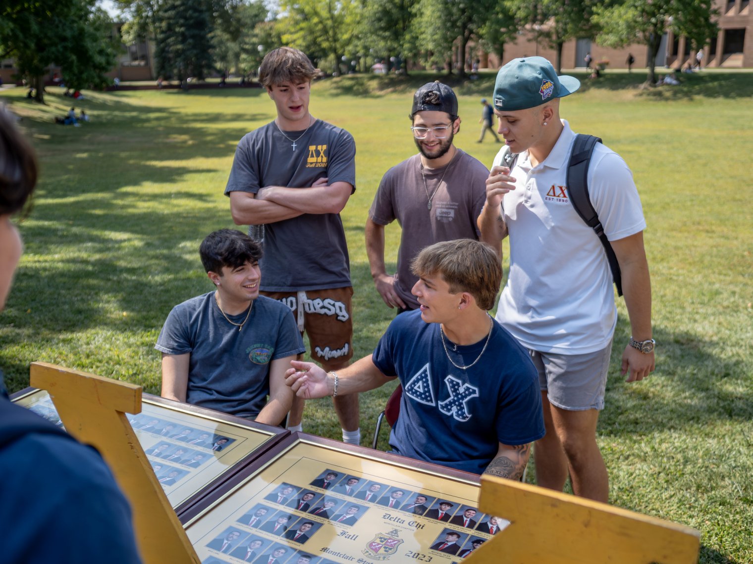 Five male students are behind a table with their fraternity.