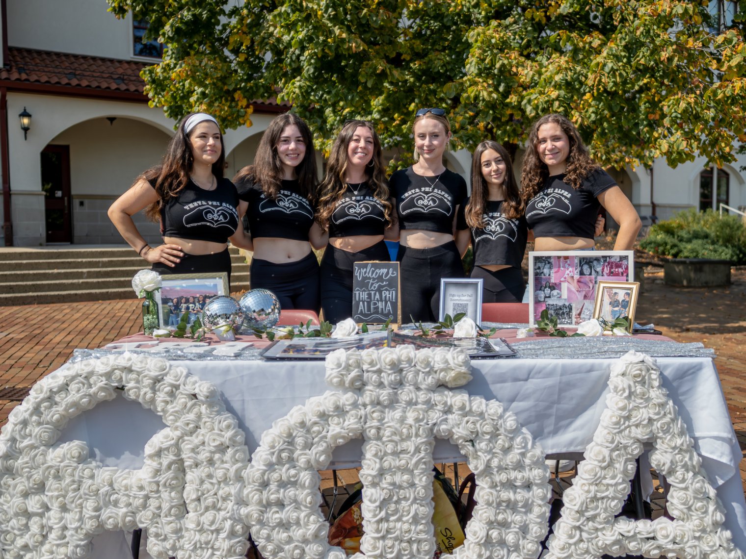 Group of female students posing behind a table with their Sorority Logo in front.