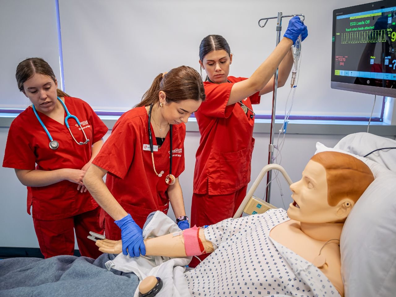 Three nurses connecting a simulant to an IV line