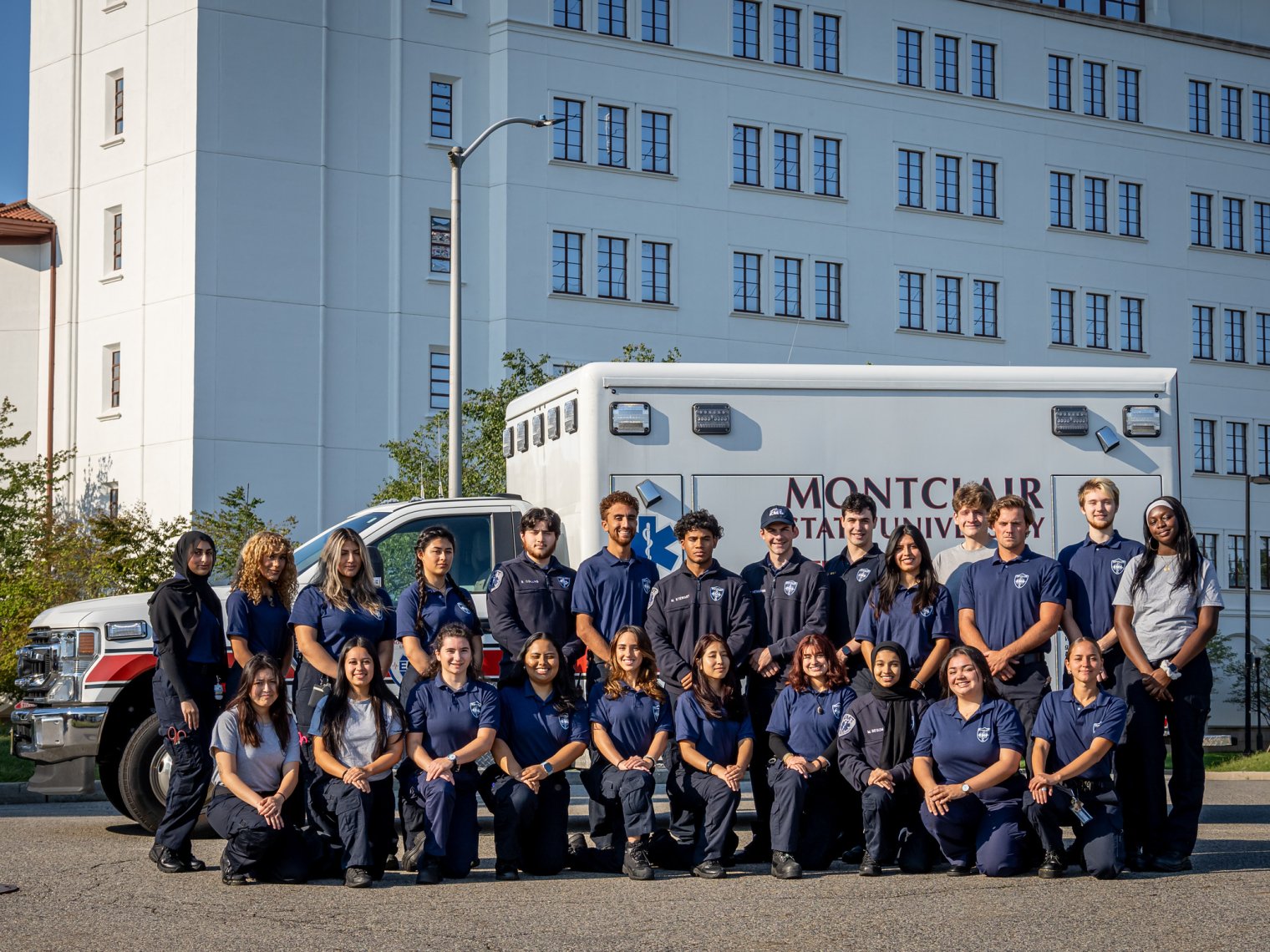 Group of EMS students in front of an ambulance with Montclair State University on the side of the truck.
