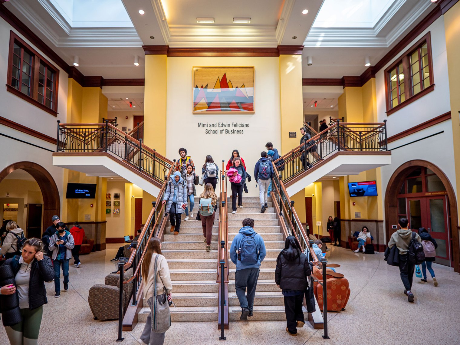 Crowd of students walking up and down the stairs of the Feliciano School of Business building.