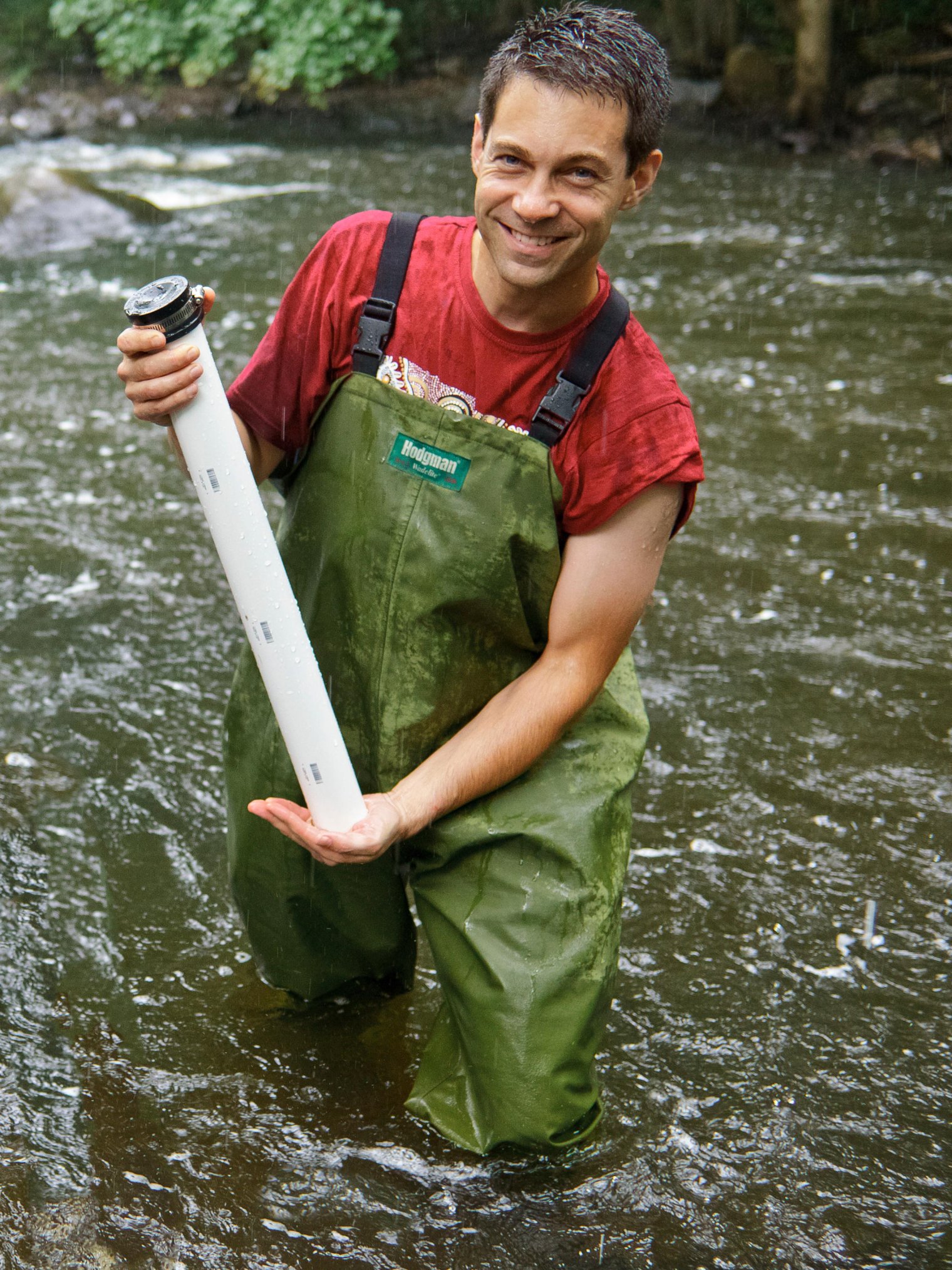Man in water smiling with contraption for collecting samples.