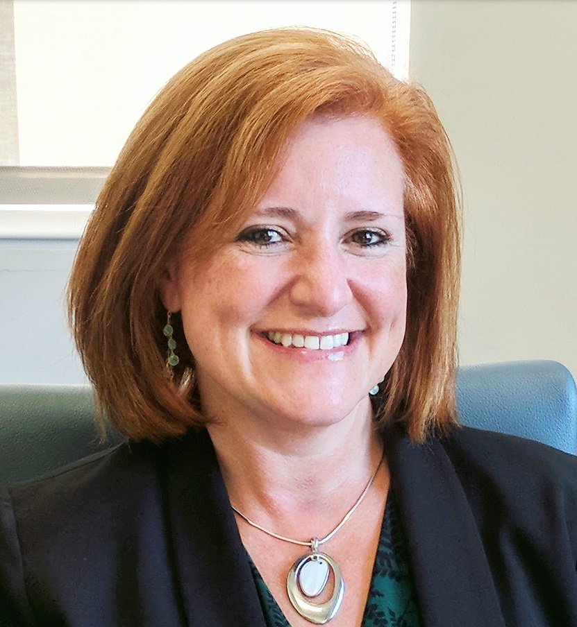 Woman smiling with red hair posing for a headshot.