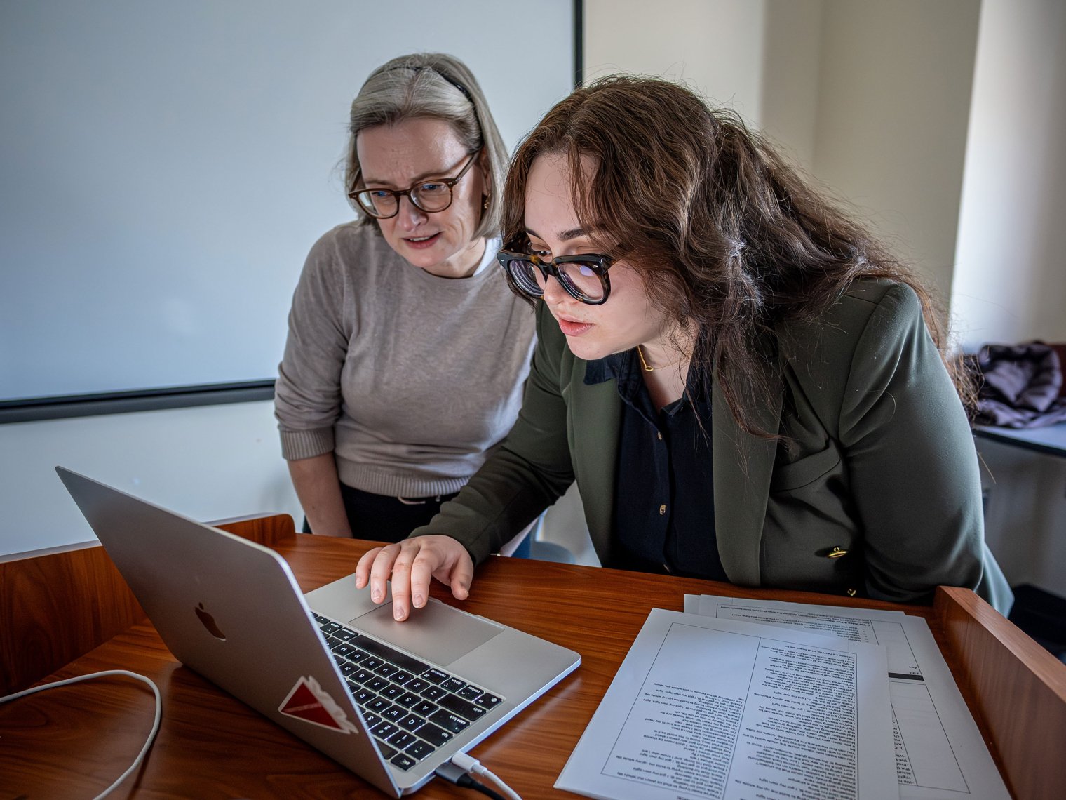 Ana Barahona and Religion Professor Julia Berger review a lesson plan on a laptop.