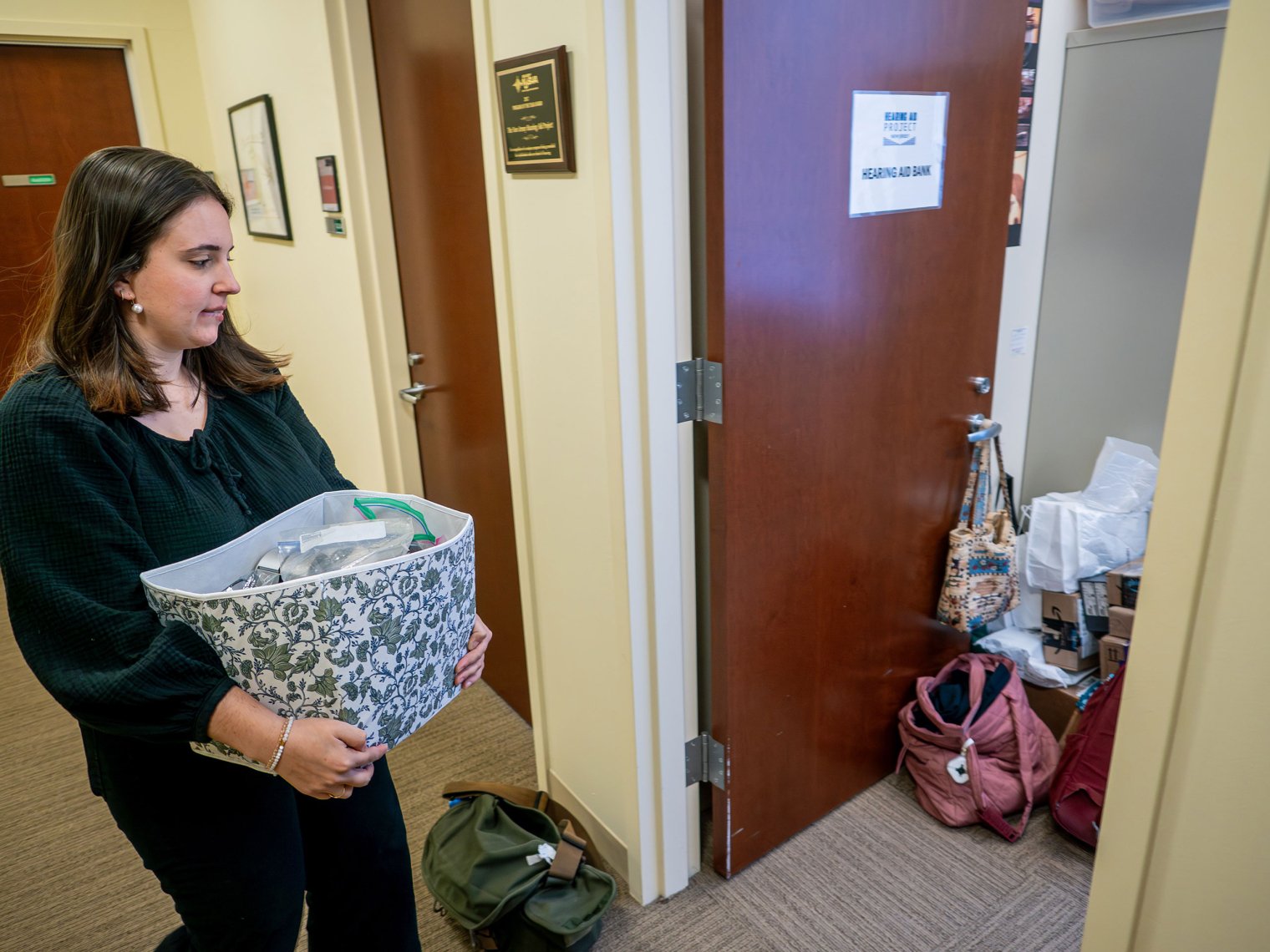 Julianna Mijal carries a container of donated hearing aids to the bank for refurbishing.