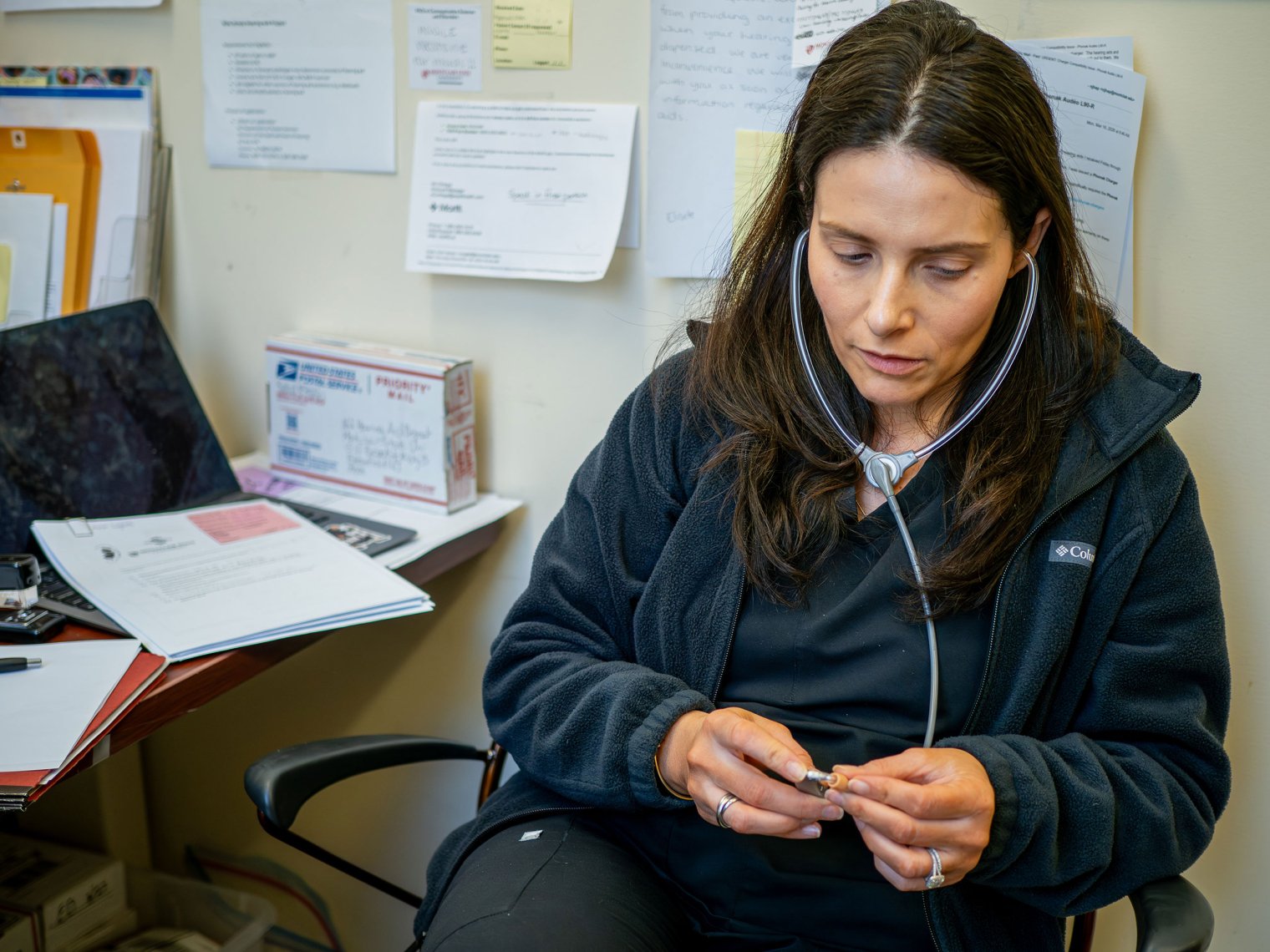 Elena Kagan-Weitz tests a hearing aid using a stethoscope.