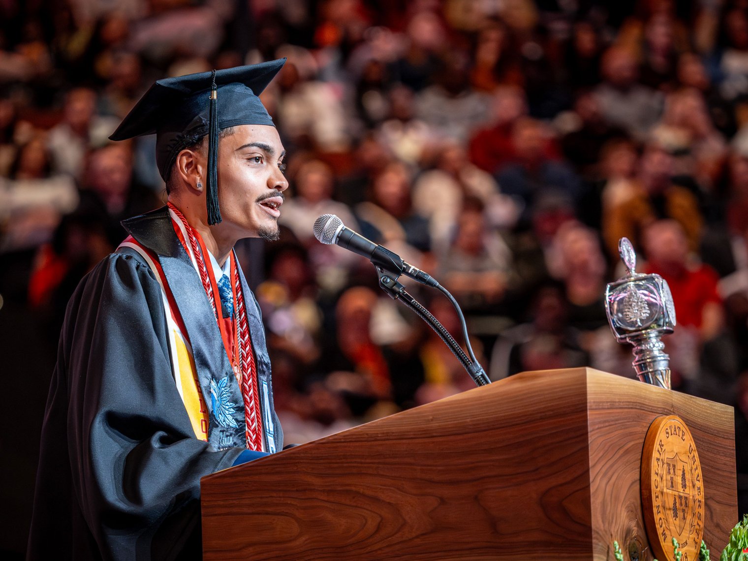 In cap and gown,Ethan Garcia speaks from a lectern on commencement day.